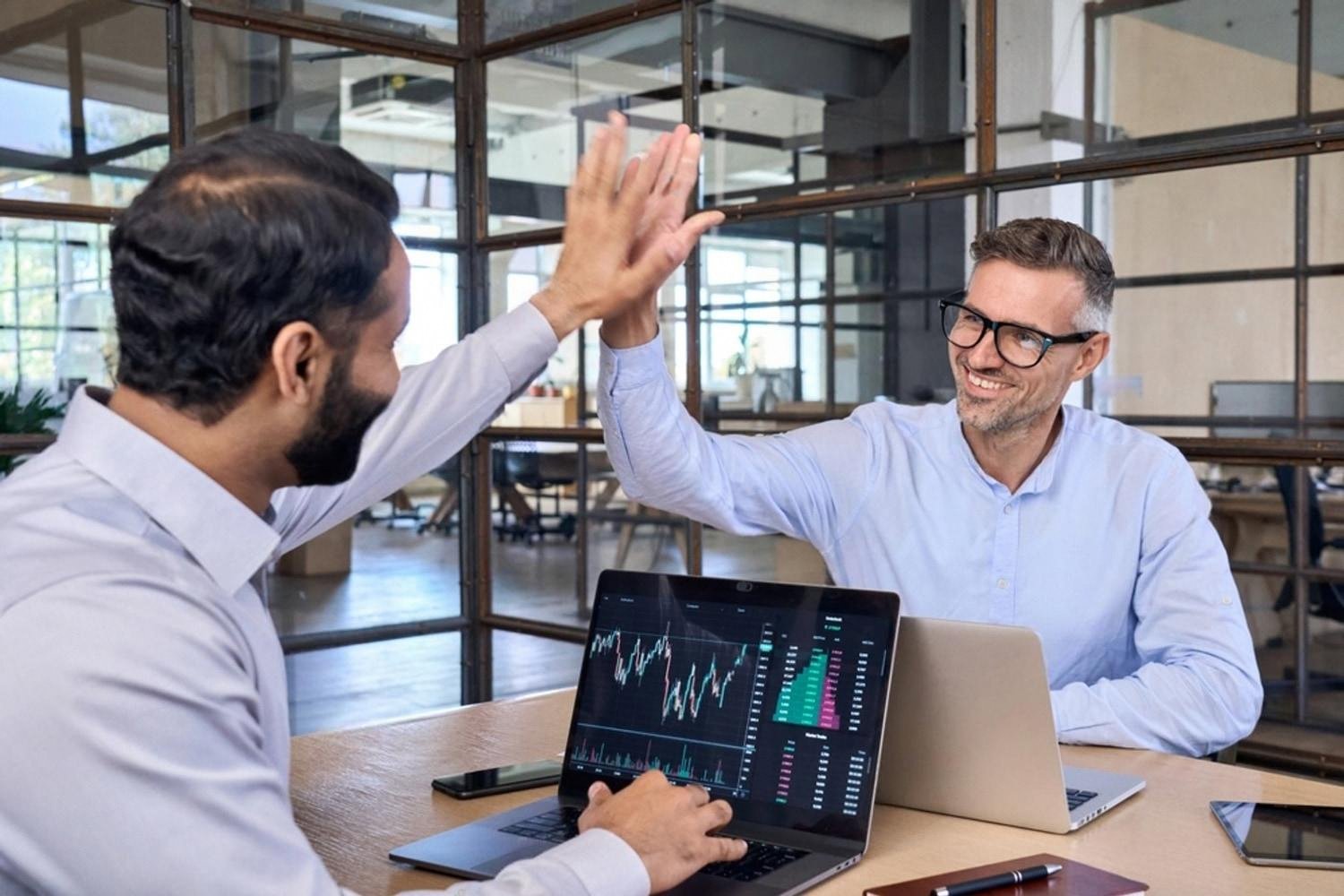 Two colleagues in a UAE office celebrating a positive engagement result with a high five